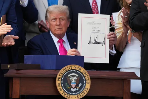 Trump holding up the signed bill at a Rose Garden ceremony