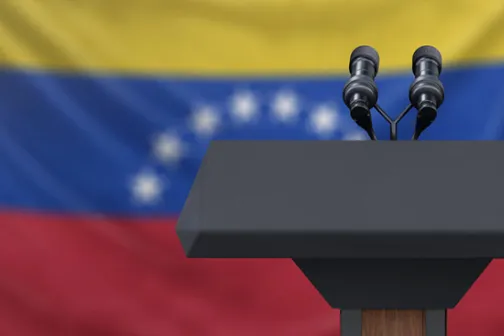 A podium with microphones in front of the Venezuelan flag